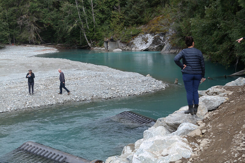 woman standing on gravel next to a blue glacial-fed lake